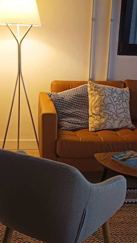 Sala de estar moderna con sofá naranja, sillón gris, lámpara de pie y cojines decorativos