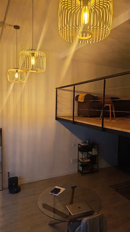 Loft moderno con lámparas doradas colgantes, mezzanine con barandilla metálica y piso de madera